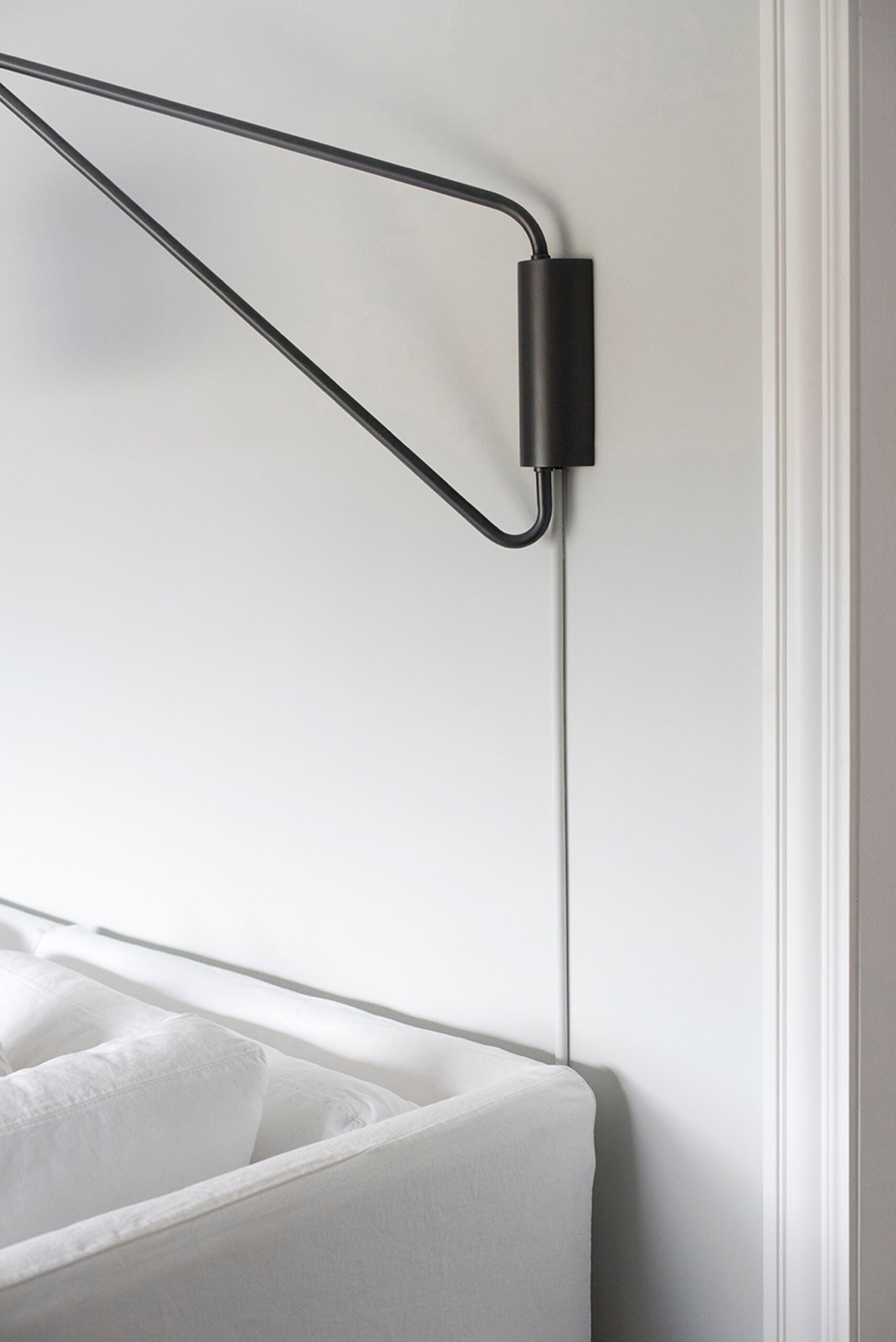 Sconce with a neatly covered cord above living room sofa